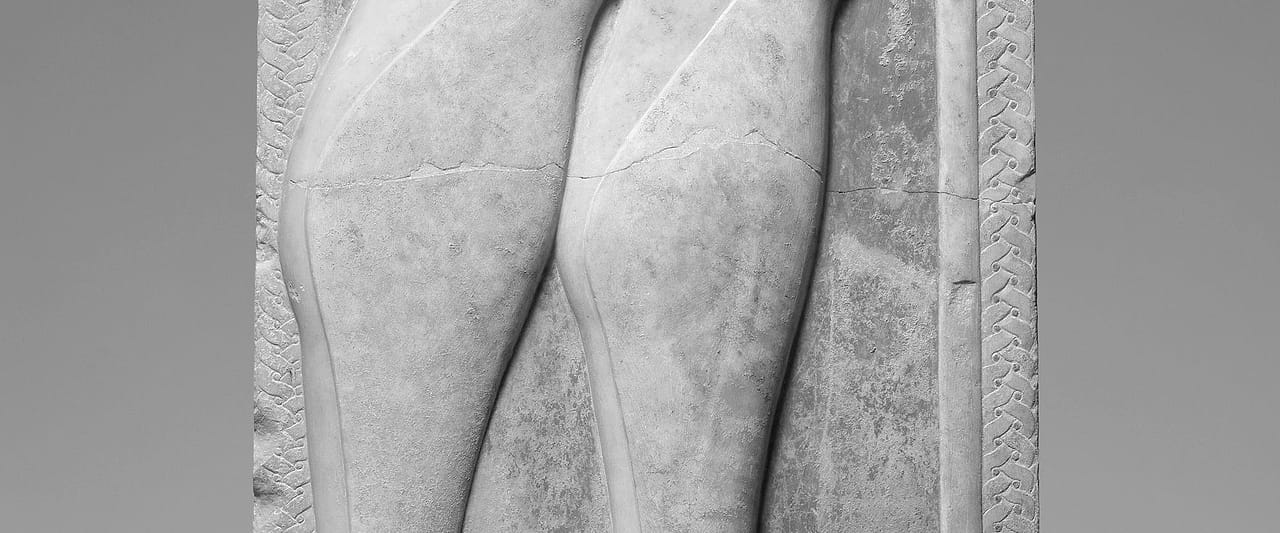 A fragment of a carved marble grave marker, the surface pitted with age.
